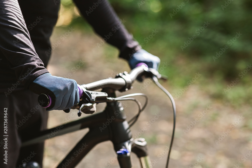 Sportsman holding bike handle on woods background Sportsman holding bike handle on woods background