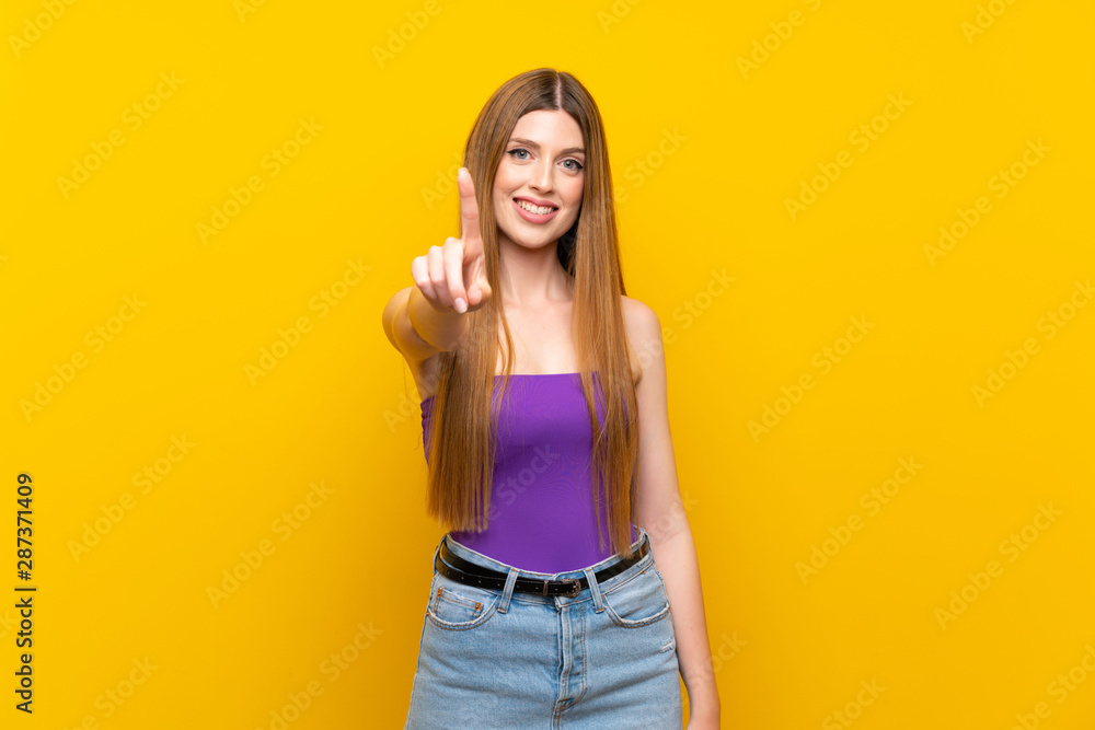 Young woman over isolated yellow background showing and lifting a finger Young woman over isolated yellow background showing and lifting a finger