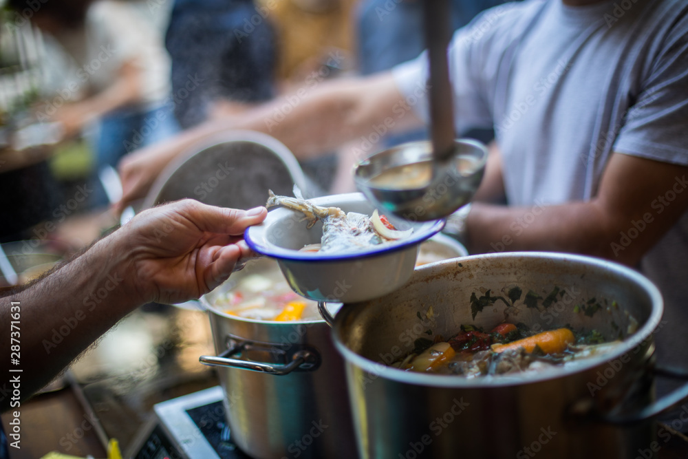 Person serving a portion of fish soup Person serving a portion of fish soup