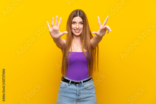 Young woman over isolated yellow background counting eight with fingers