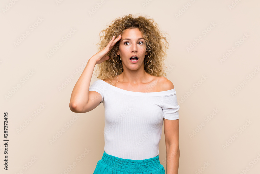 Young blonde woman with curly hair over isolated background has just realized something and has intending the solution Young blonde woman with curly hair over isolated background has just realized something and has intending the solution