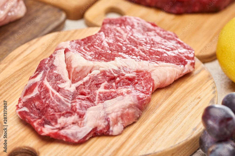 Close up view of raw meat on light wooden cutting board