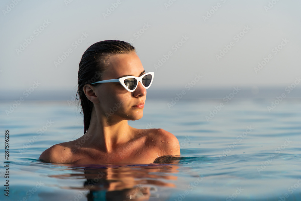 Summer portrait of a beautiful girl with sunglasses in the swimming pool  Stock Photo | Adobe Stock