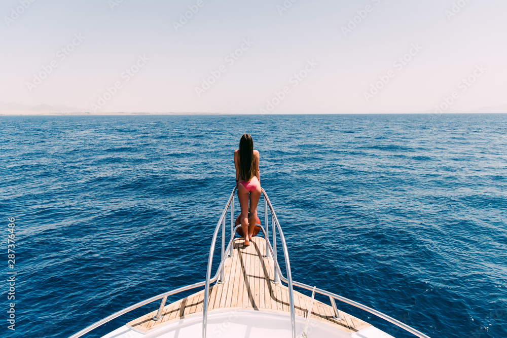 Young beautiful young woman standing on the deck of a yacht at sea.