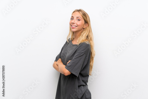 Blonde young woman over isolated white background with arms crossed and looking forward