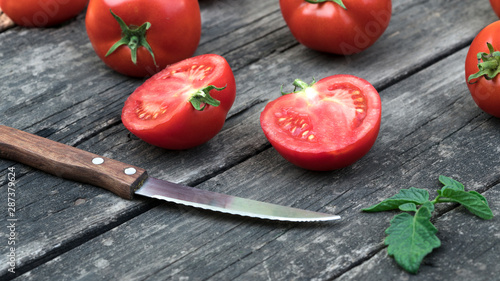 Cutting tomato cherry and some tomatoes on wooden background.