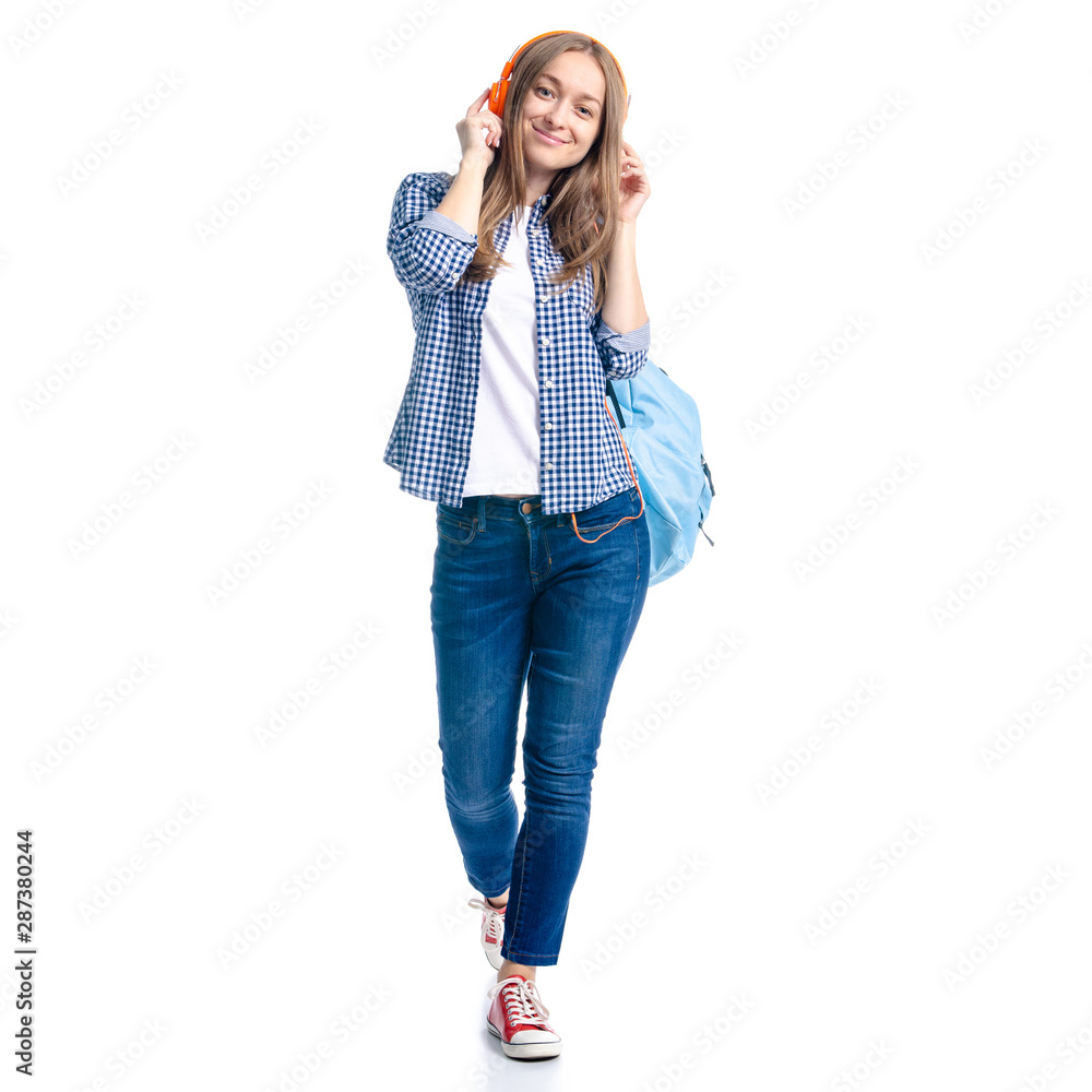 Woman in casual clothing student with backpack standing looking smiling, listening to music headphones on white background isolation Woman in casual clothing student with backpack standing looking smiling, listening to music headphones on white background isolation