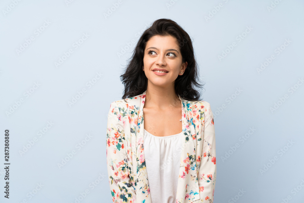 Young woman over isolated blue background laughing and looking up Young woman over isolated blue background laughing and looking up