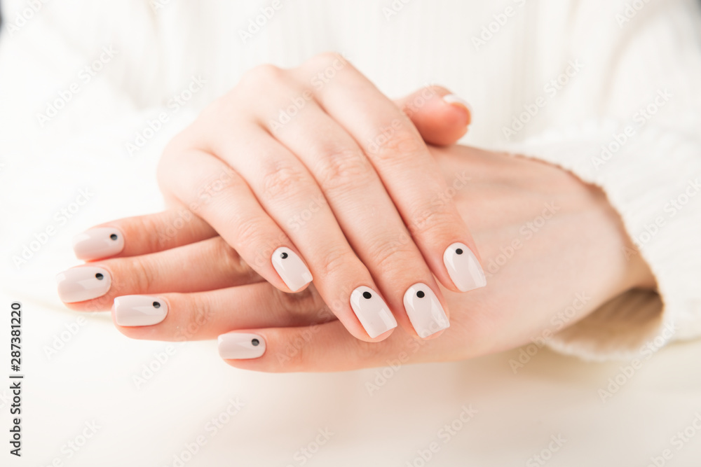 Fototapeta premium hand with beige manicure with dots nail design..