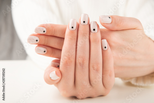 hand with beige manicure with dots nail design..