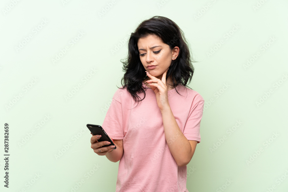 Young woman over isolated green background thinking and sending a message Young woman over isolated green background thinking and sending a message
