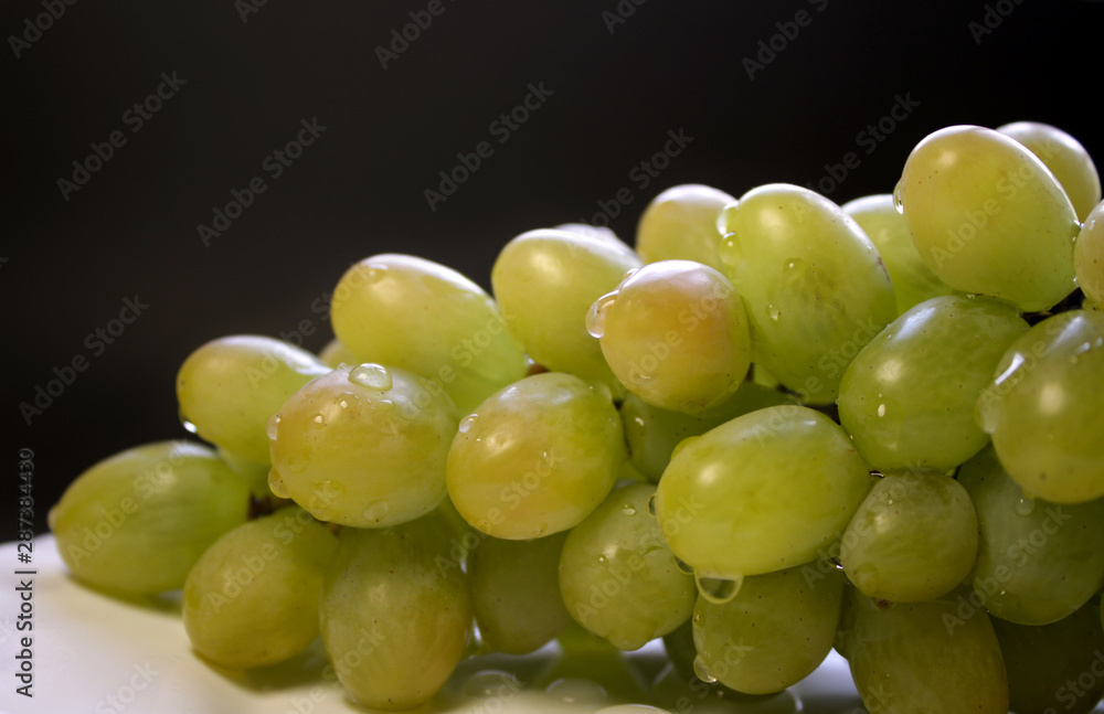 Bunch of green grape isolated on a plate on a black background