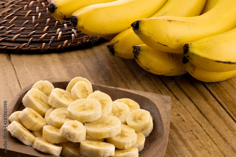 banana slices in rustic pot with bunch of bananas in the background banana slices in rustic pot with bunch of bananas in the background