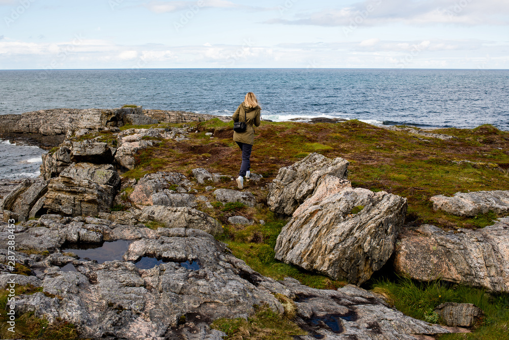 Blond hair woman enjoy beautiful nature landscape in North. Ocean and mountain. Tourist landmark in Norway. Amazing scenic outdoors view. Travel, adventure, relax lifestyle. Lofoten Islands