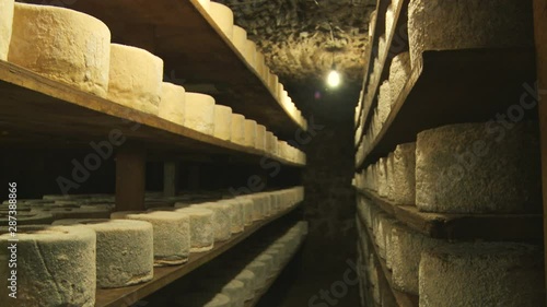 Castelmagno seasoned organic cow cheeses ripening on a shelves in a cave tilt photo