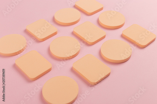 A lot of sponge, a beautiful blender for applying foundation or powder. Flat lay on a pink background, copy space.