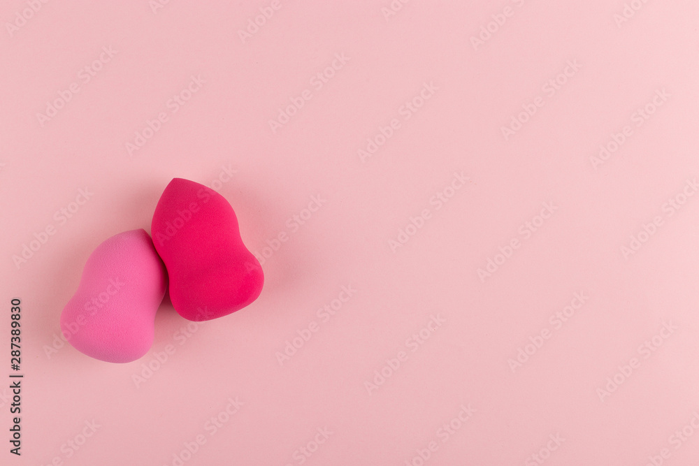 Girl hand holds a beauty makeup blender on a pink background, copy space. Girl hand holds a beauty makeup blender on a pink background, copy space.
