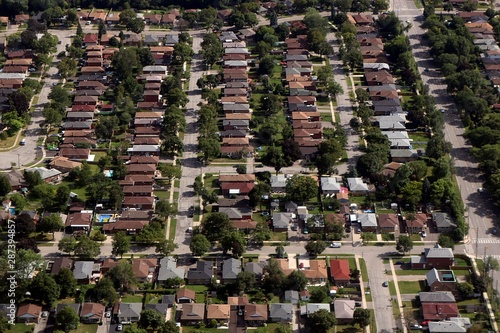 Arial view of house rooftops and city blocks near Toronto and surrounding area as commercial jet comes in to land