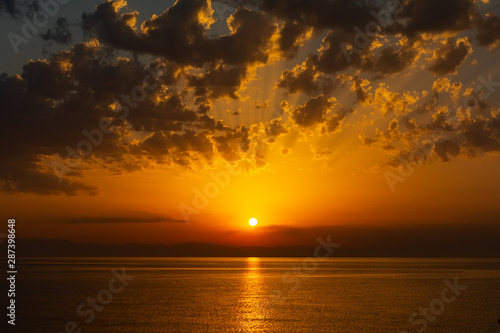 Sea landscape with sunrise, mountains and cloudy sky
