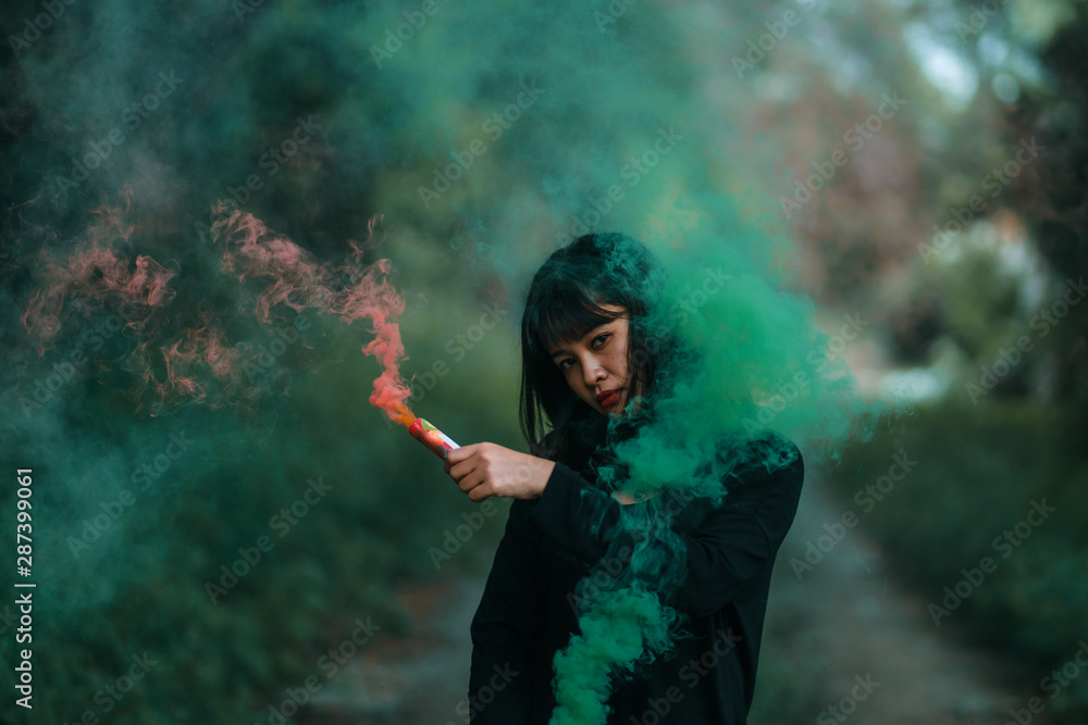 Portrait of Asian woman in black cloth with color fire smoke in forest witch concept
