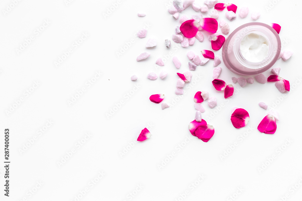 Cosmetics with sea salt and roses decoration on white background top view space for text