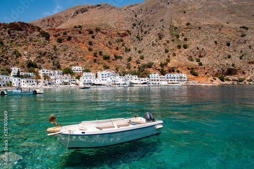 Small boats in the harbour of Loutro on Crete with torquoise waters and traditional buildings and restaurants