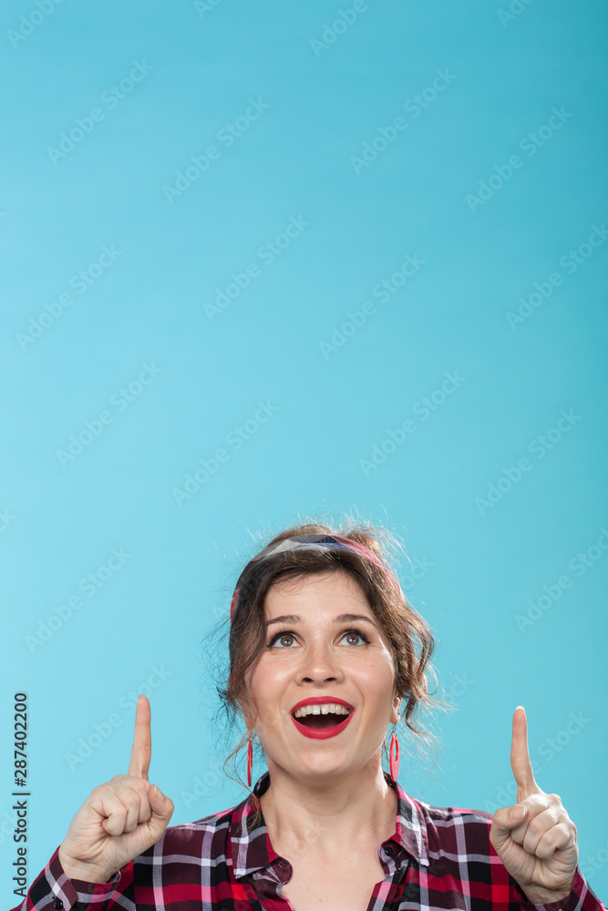 fashion and people concept - pin-up woman looking and showing up on blue background fashion and people concept - pin-up woman looking and showing up on blue background