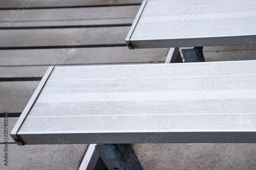 Empty metal bleachers seats in football, soccer or baseball stadium during local game