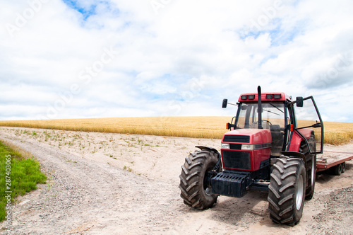 Red​ tractor with malt farm​ and cloud sky