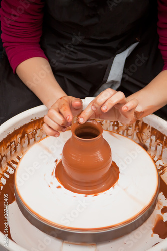Girl's hand in the process of making clay pottery on a potter's wheel.