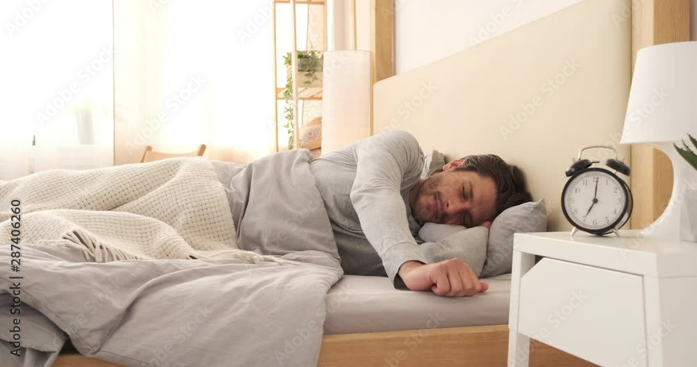 Happy man yawning and stretching after waking up early morning in bed Happy man yawning and stretching after waking up early morning in bed