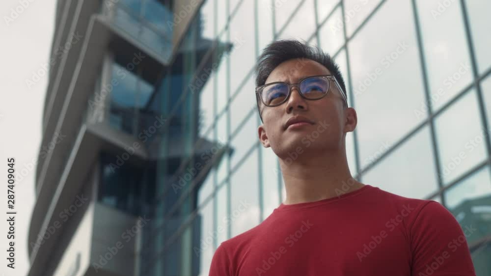 Portrait of successful young Asian business man cross hands near modern office building at urban city background. Portrait of successful young Asian business man cross hands near modern office building at urban city background.
