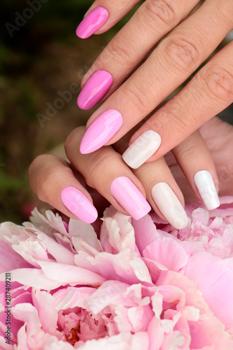 Light pink, pastel manicure on various shapes of nails with peony closeup.