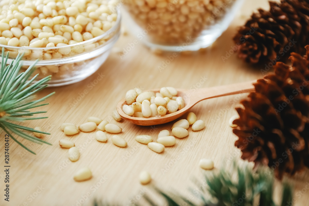 Pine nuts on a wooden spoon with cedar branches, cones on a beige background. Pine nuts on a wooden spoon with cedar branches, cones on a beige background.