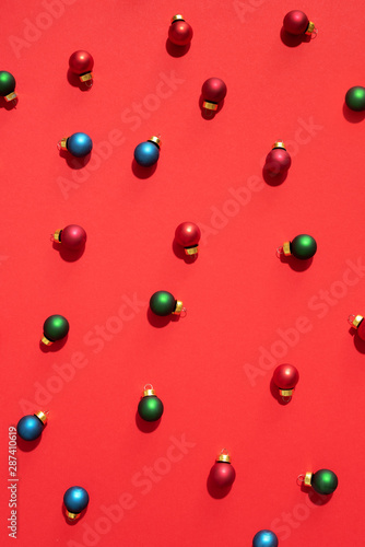 Christmas colored baubles. Festive pattern made of new year baubles on red background. Flat lay  top view. Minimal design greeting card
