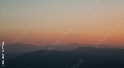 background photograph of a sunset in the mountains, on the Gran Sasso in Italy, with beautiful orange yellow green brown colors - image