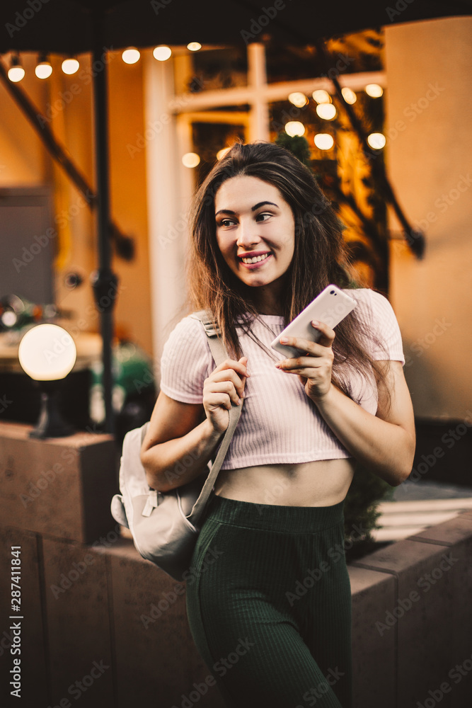 Smiling woman using phone and drink coffee on the street in summer day. Smiling woman using phone and drink coffee on the street in summer day.