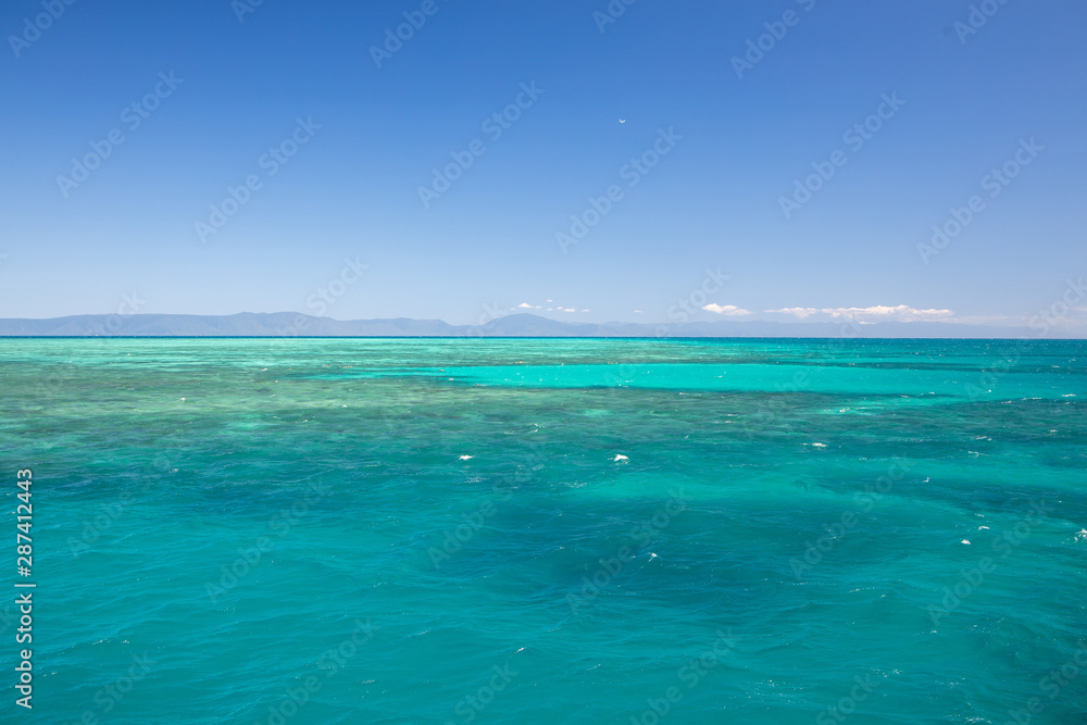 The Beautiful Great Barrier Reef from Above Aerial of Coral and Australia Mountains in Background with Blue Sky in Summer Weather