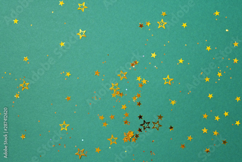 Golden star sparkles on green background. Christmas and New year concept. Festive backdrop with copy space