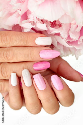 Light pink  pastel manicure on various shapes of nails with peony closeup.