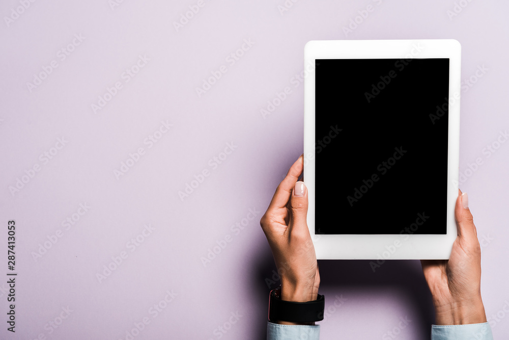 cropped view of woman holding digital tablet with blank screen on purple cropped view of woman holding digital tablet with blank screen on purple