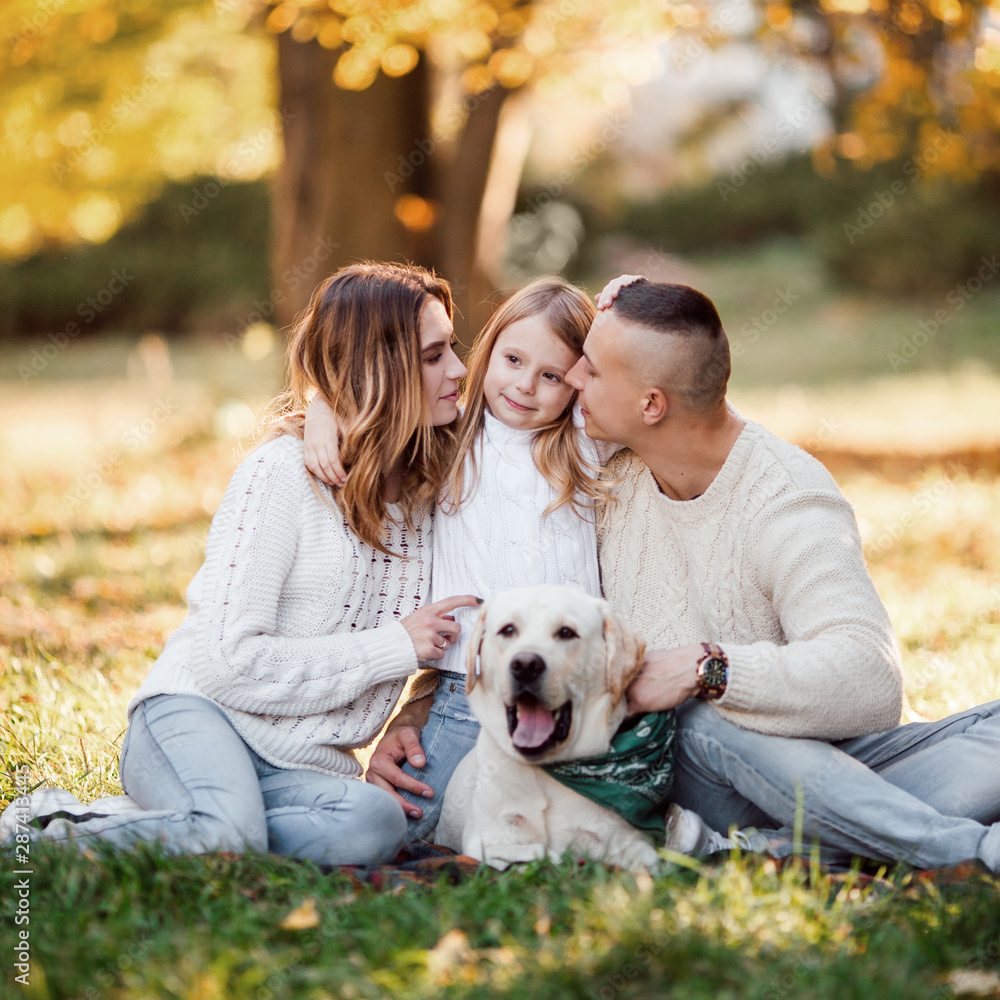 Happy beautiful family with dog labrador is having fun are sitting on green grass in park. Happy beautiful family with dog labrador is having fun are sitting on green grass in park.