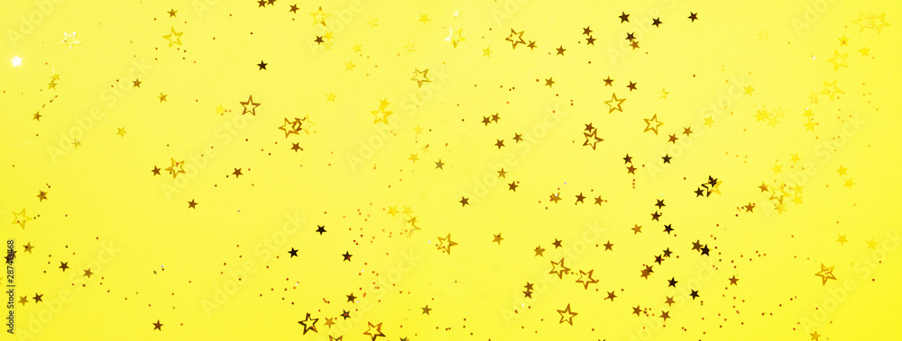 Golden star sparkles on yellow background. Christmas and New year concept. Festive backdrop with copy space