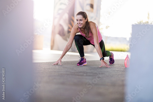Fototapeta Naklejka Na Ścianę i Meble -  Young woman doing stretching exercise in urban area