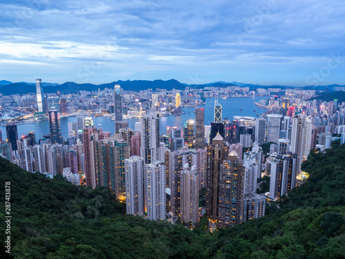 Hong Kong Skyline at Sunset from the Famous Victoria Point at Daytime. Green forest and river surrounded by towering sky scrapers which is densly populated