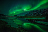 Aurora borealis (Northern Lights) reflected in partially frozen lake, North Snaefellsnes, Iceland
