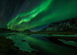 Aurora borealis (Northern Lights) reflected in partially frozen lake, North Snaefellsnes, Iceland