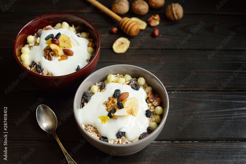 Muesli with milk, nuts, dried fruits on wooden brown background Muesli with milk, nuts, dried fruits on wooden brown background