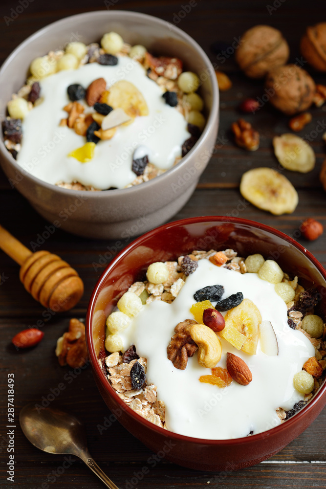 Muesli with milk, nuts, dried fruits on wooden brown background Muesli with milk, nuts, dried fruits on wooden brown background
