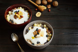 Muesli with milk, nuts, dried fruits on wooden brown background